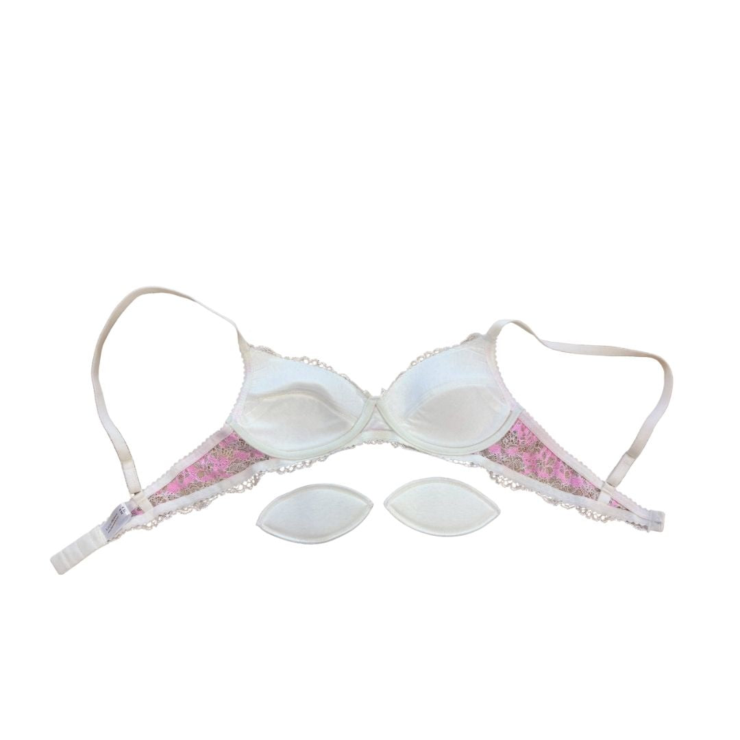 White underwire bra with pink floral lace trim and three matching white cup pads, displayed on a solid white background.