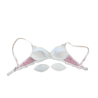 White underwire bra with pink floral lace trim and three matching white cup pads, displayed on a solid white background.